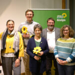 Gruppenfoto mit Blumenstrauß vor Banner mit Logo Grüne Ostallgäu